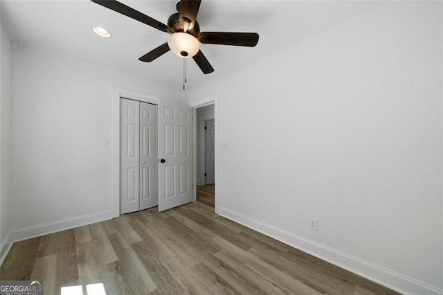 unfurnished bedroom featuring ceiling fan, light hardwood / wood-style floors, and a closet