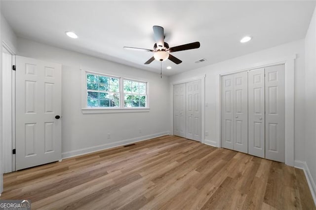 unfurnished bedroom with two closets, ceiling fan, and light hardwood / wood-style flooring