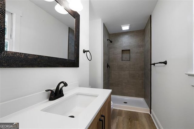 bathroom with tiled shower, wood-type flooring, and vanity