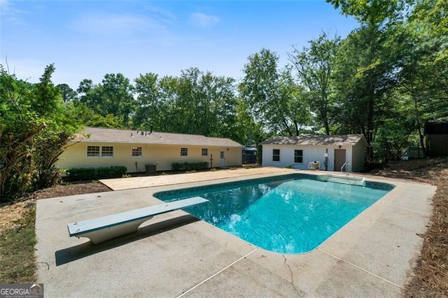 view of pool with an outbuilding, a diving board, and a patio area