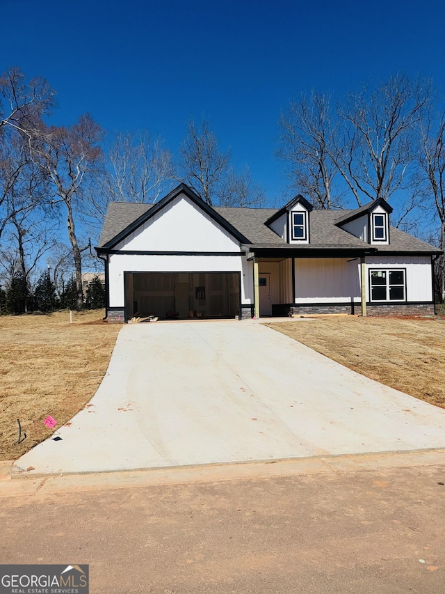 modern farmhouse featuring an attached garage, driveway, and a front lawn