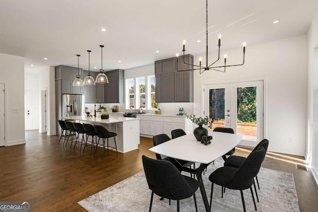 dining area with french doors, dark hardwood / wood-style flooring, plenty of natural light, and a notable chandelier