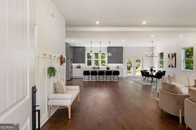 living room with dark wood-type flooring, beam ceiling, and a chandelier