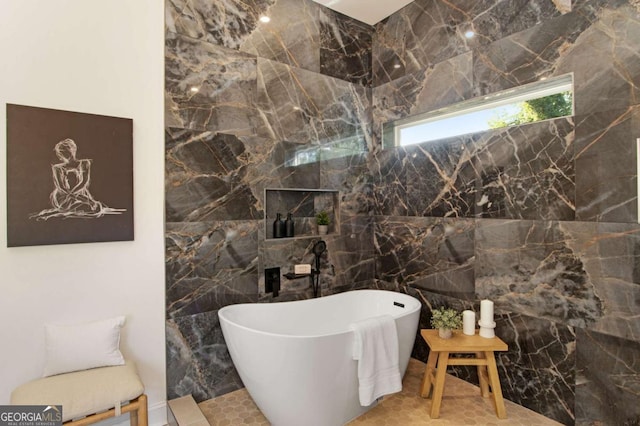 bathroom featuring tile walls, a washtub, and tile patterned flooring