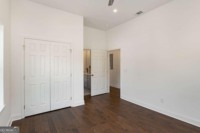 unfurnished bedroom with ceiling fan, dark wood-type flooring, a closet, and electric panel