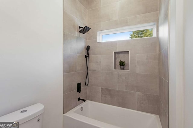 bathroom with toilet and tiled shower / bath