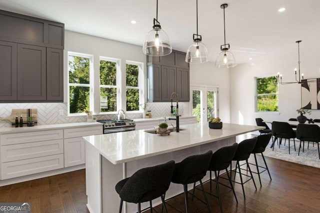 kitchen featuring a large island with sink, decorative light fixtures, and decorative backsplash