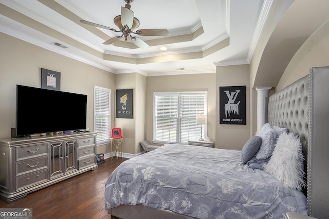 bedroom featuring decorative columns, a raised ceiling, ceiling fan, ornamental molding, and dark hardwood / wood-style floors