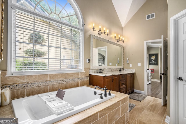 bathroom featuring lofted ceiling, tiled tub, and vanity