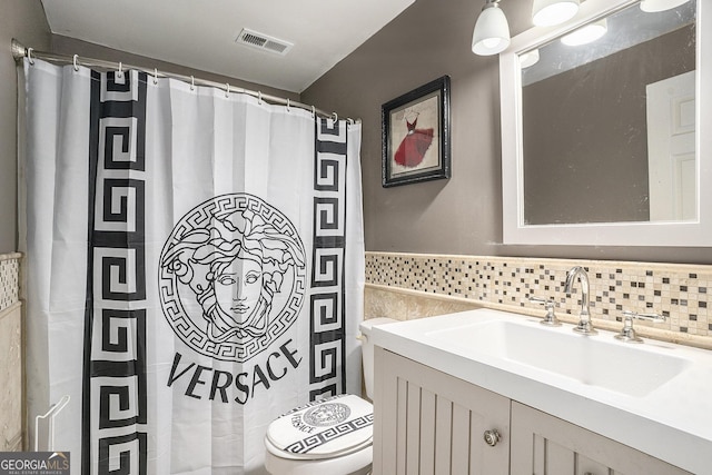 bathroom featuring toilet, tasteful backsplash, and vanity