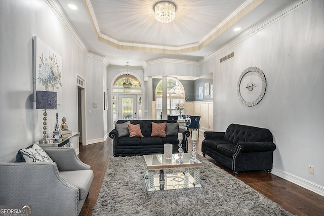 living room with a chandelier, a tray ceiling, ornamental molding, and dark hardwood / wood-style floors