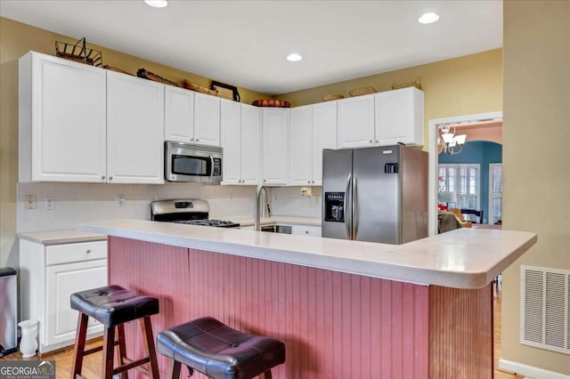 kitchen featuring a breakfast bar area, white cabinetry, and appliances with stainless steel finishes