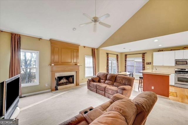 living room with a high end fireplace, high vaulted ceiling, ceiling fan, and a wealth of natural light