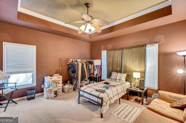 carpeted bedroom with ceiling fan and a raised ceiling