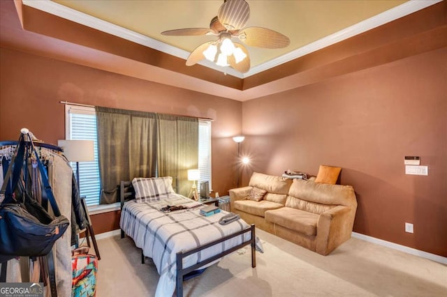 bedroom featuring ceiling fan, a tray ceiling, crown molding, and light colored carpet