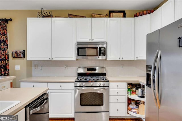 kitchen featuring stainless steel appliances, white cabinetry, and backsplash