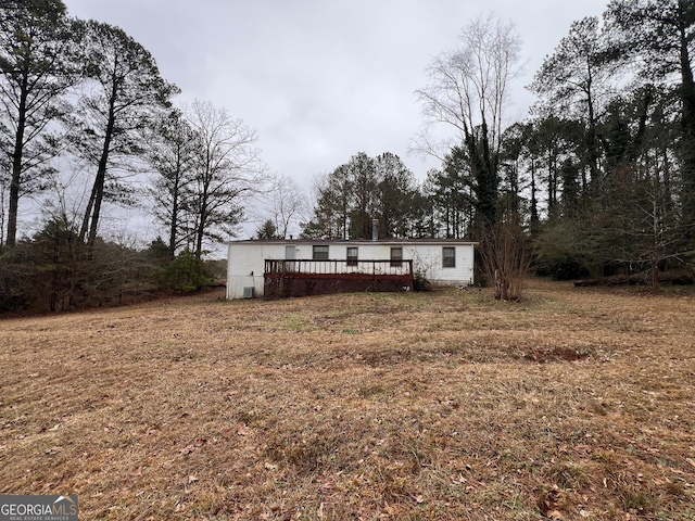 back of property featuring a deck and a lawn