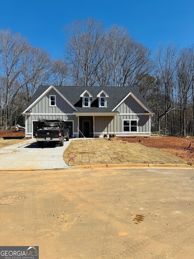 view of front of house with an attached garage, concrete driveway, board and batten siding, and roof with shingles