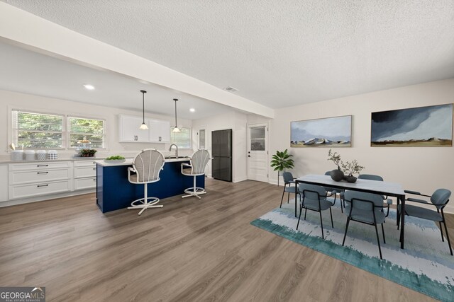 kitchen featuring decorative light fixtures, white cabinetry, a breakfast bar area, and light wood-type flooring