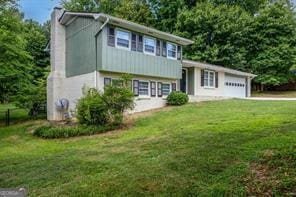 split level home with a garage, a front lawn, and a chimney