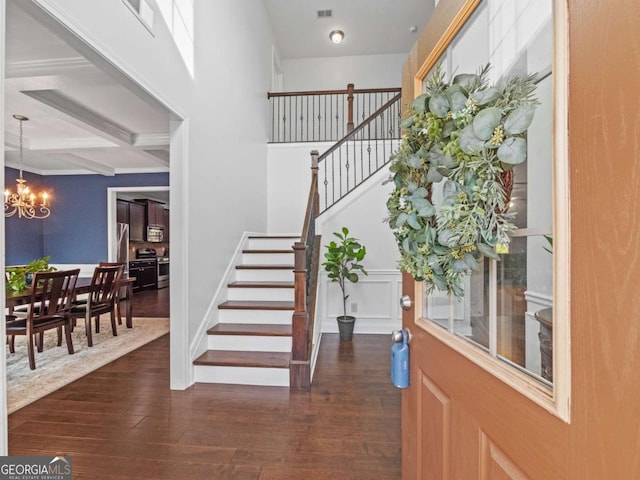 entrance foyer with beam ceiling, dark hardwood / wood-style flooring, coffered ceiling, and a chandelier