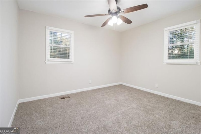 carpeted empty room featuring ceiling fan and plenty of natural light