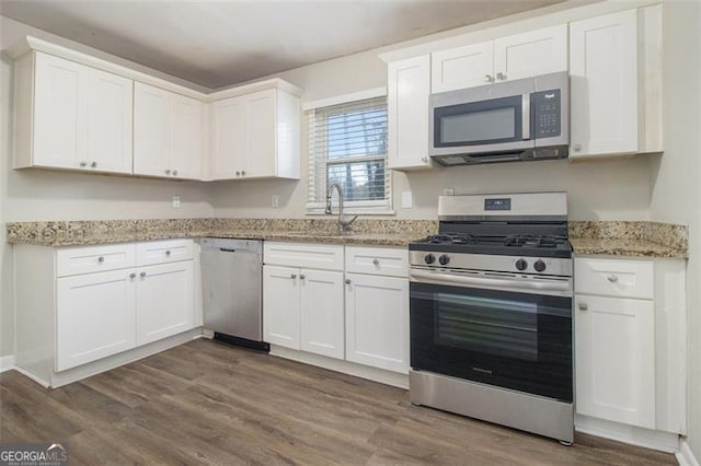 kitchen with appliances with stainless steel finishes, white cabinetry, sink, and wood-type flooring