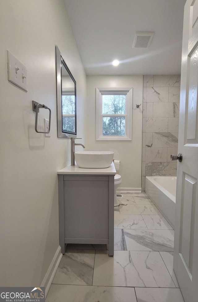 full bathroom with toilet, tiled shower / bath, and vanity