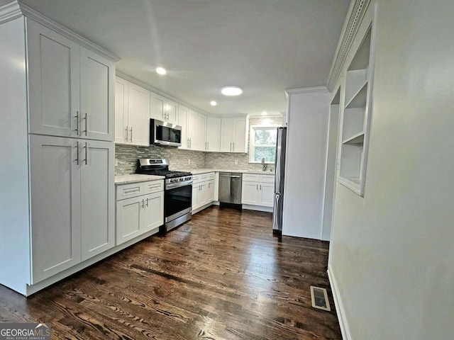 kitchen with white cabinets, appliances with stainless steel finishes, crown molding, and dark hardwood / wood-style floors