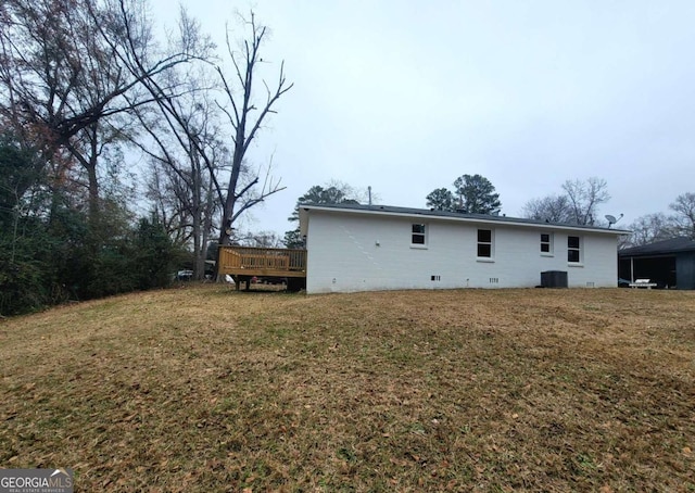 back of property with a wooden deck, cooling unit, and a lawn