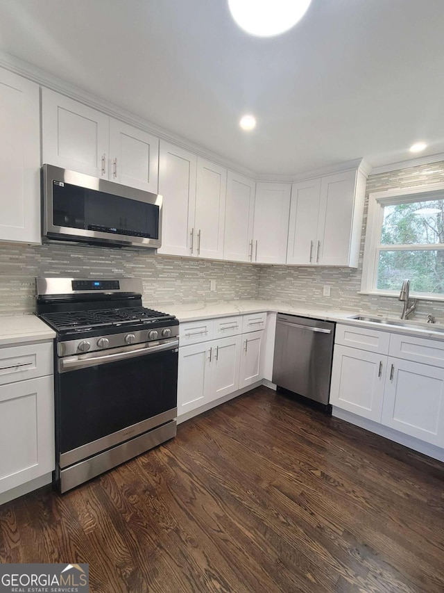 kitchen with white cabinetry, stainless steel appliances, sink, backsplash, and dark hardwood / wood-style floors