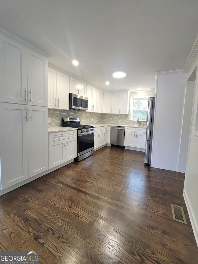 kitchen featuring appliances with stainless steel finishes, sink, white cabinetry, and dark hardwood / wood-style floors