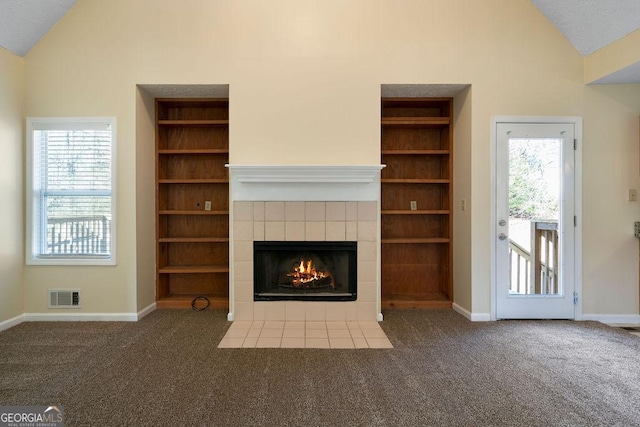 unfurnished living room with a tile fireplace, built in features, and dark carpet