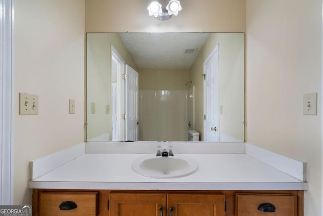 bathroom featuring vanity, a shower, and toilet