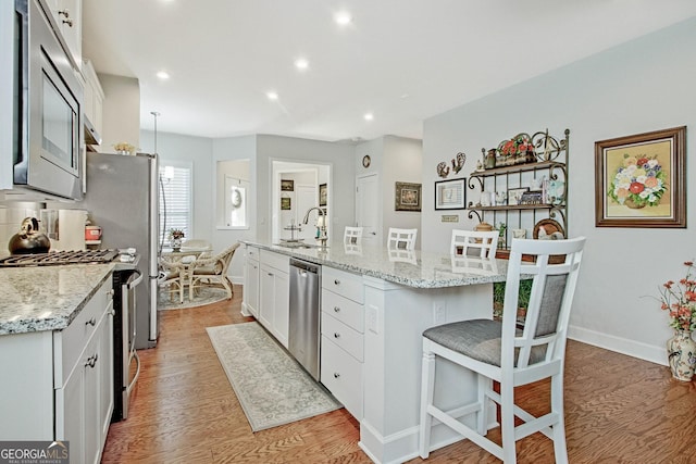 kitchen featuring an island with sink, a kitchen bar, white cabinetry, appliances with stainless steel finishes, and sink