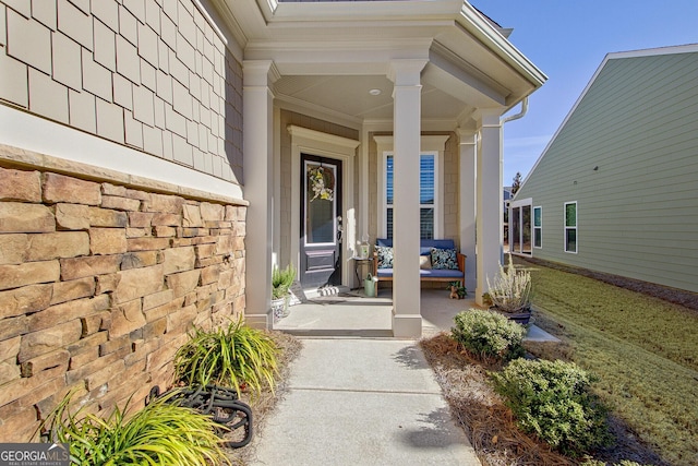 view of exterior entry featuring covered porch and a yard