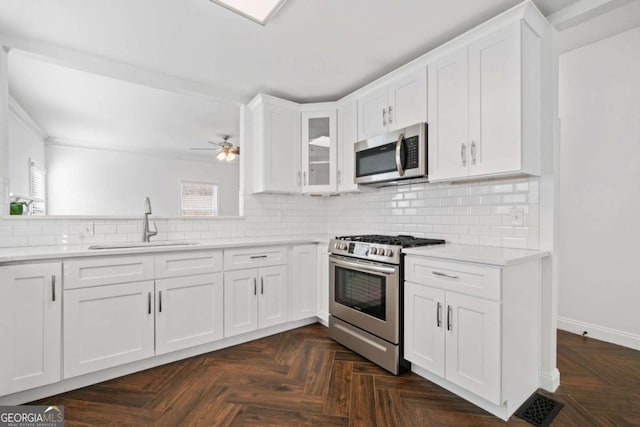 kitchen featuring stainless steel appliances, white cabinets, sink, and ceiling fan