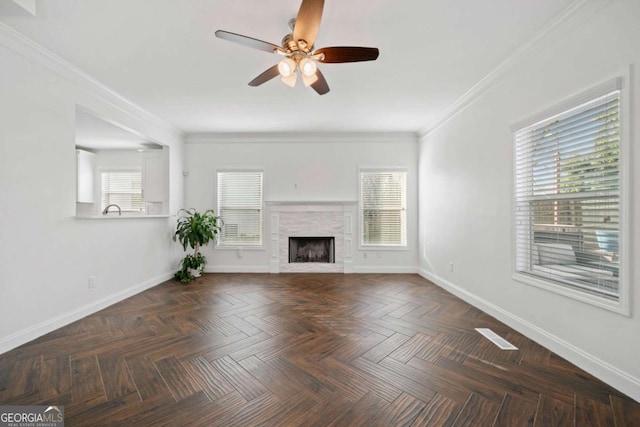 unfurnished living room featuring dark parquet flooring, ceiling fan, ornamental molding, and a tiled fireplace