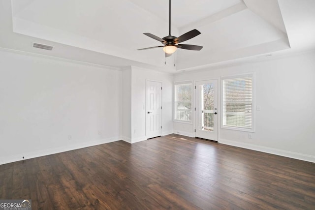 spare room featuring ceiling fan, dark wood-type flooring, and a raised ceiling