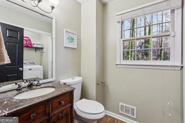 bathroom featuring washer / dryer, toilet, vanity, and hardwood / wood-style flooring