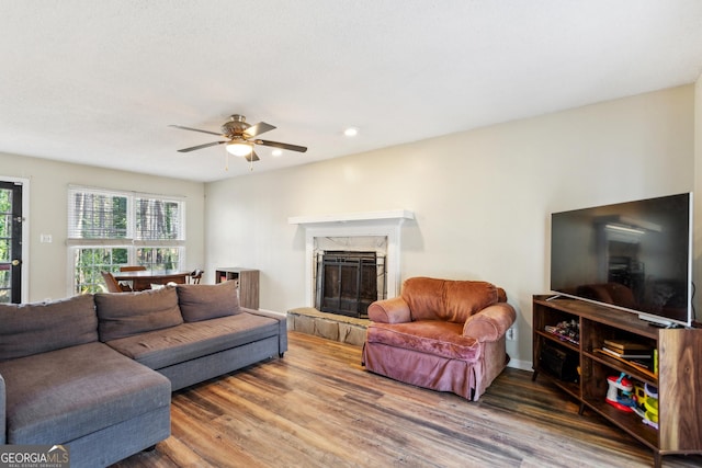 living room with a premium fireplace, ceiling fan, and hardwood / wood-style flooring