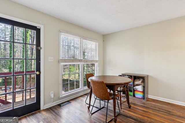 dining space with a textured ceiling and dark hardwood / wood-style floors