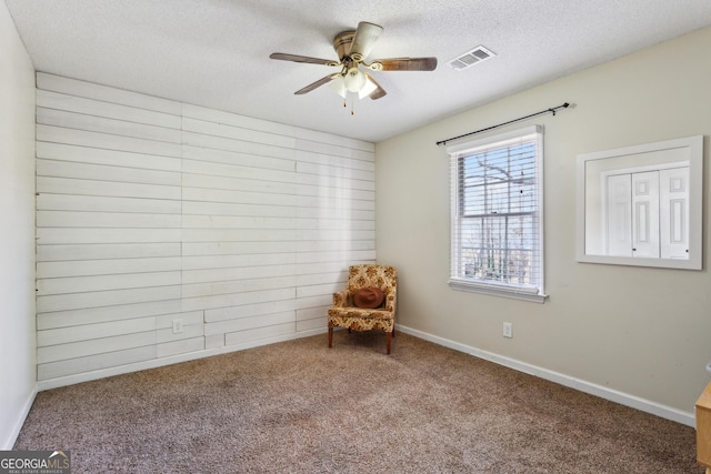 unfurnished room featuring a textured ceiling, carpet floors, and ceiling fan