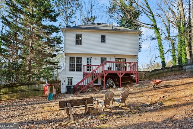 back of property with an outdoor fire pit and a deck