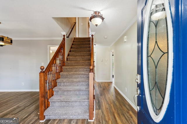 foyer with dark hardwood / wood-style flooring, a textured ceiling, and crown molding