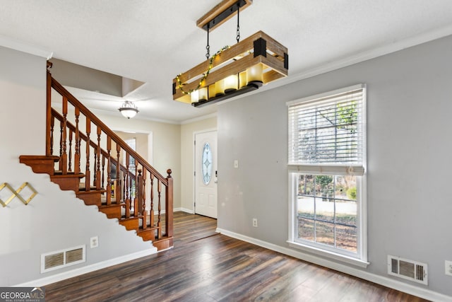 foyer entrance with a textured ceiling, ornamental molding, and dark hardwood / wood-style flooring