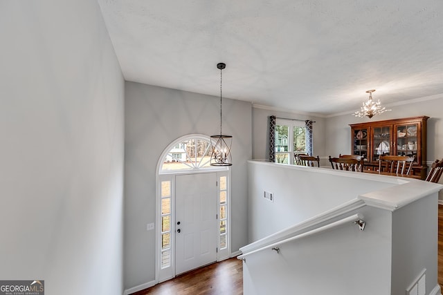 foyer with dark wood-type flooring, a textured ceiling, and a notable chandelier