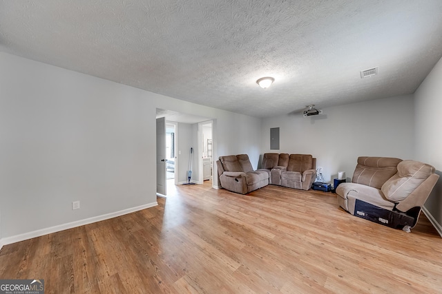 living room with a textured ceiling, light hardwood / wood-style floors, and electric panel