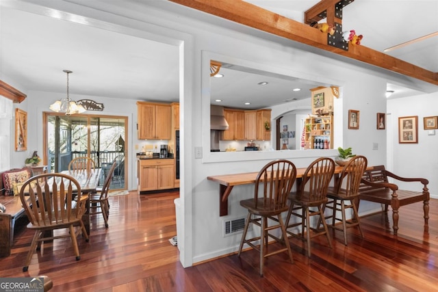 kitchen with kitchen peninsula, dark hardwood / wood-style floors, decorative light fixtures, a notable chandelier, and wall chimney range hood