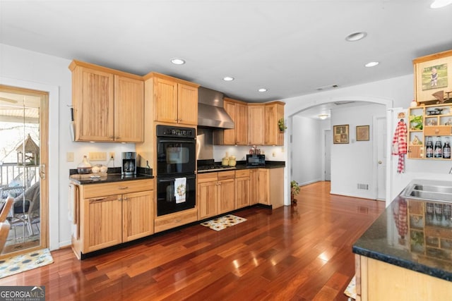 kitchen featuring sink, double oven, stainless steel gas stovetop, dark hardwood / wood-style flooring, and wall chimney range hood